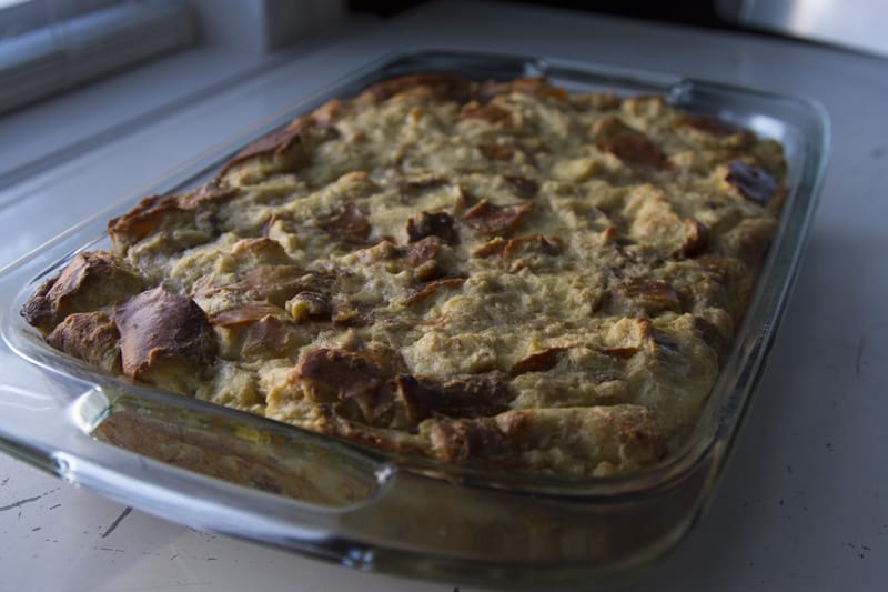 Finished pretzel bread pudding in a glass baking dish cooling on a white table top near a window. 