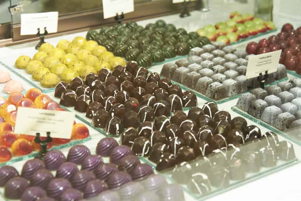 A variety of chocolates in various colors and shapes in a candy case.