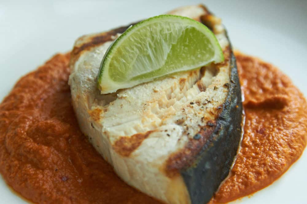 Grilled halibut with Almond orange mole, garnished with a lime wedge. 