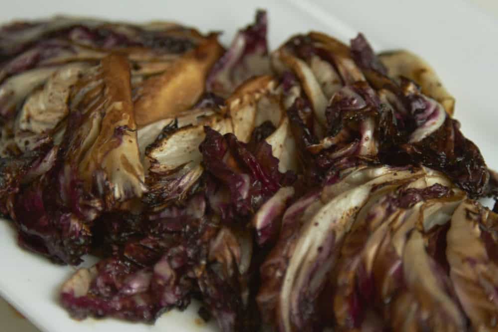 Grilled radicchio with balsamic vinegar on a white plate.