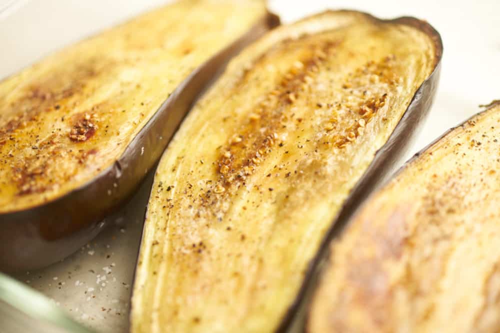 Roasted eggplant halves in a baking dish. 