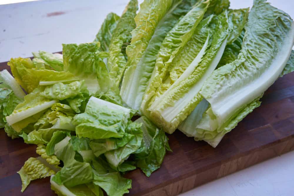 Chopped romaine lettuce on a wooden cutting board.