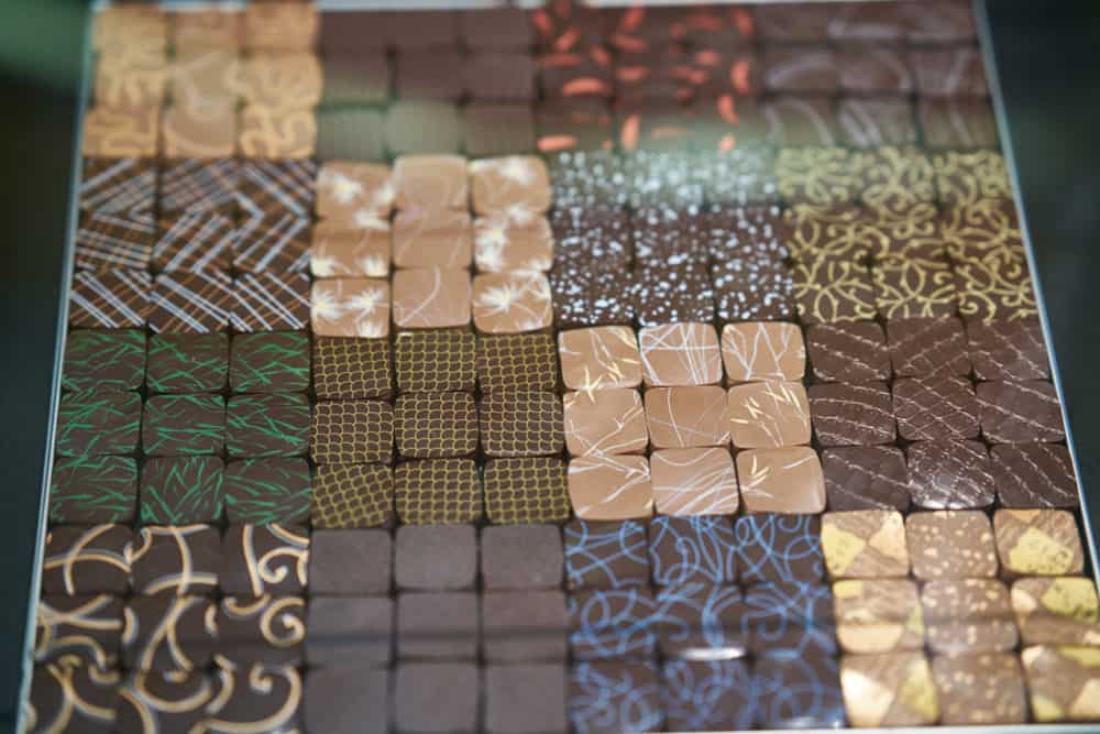 Colorfully decorated chocolates in a variety of flavors in a glass case at Jaques Genin Chocolaterie in Paris in the Marais neighborhood.