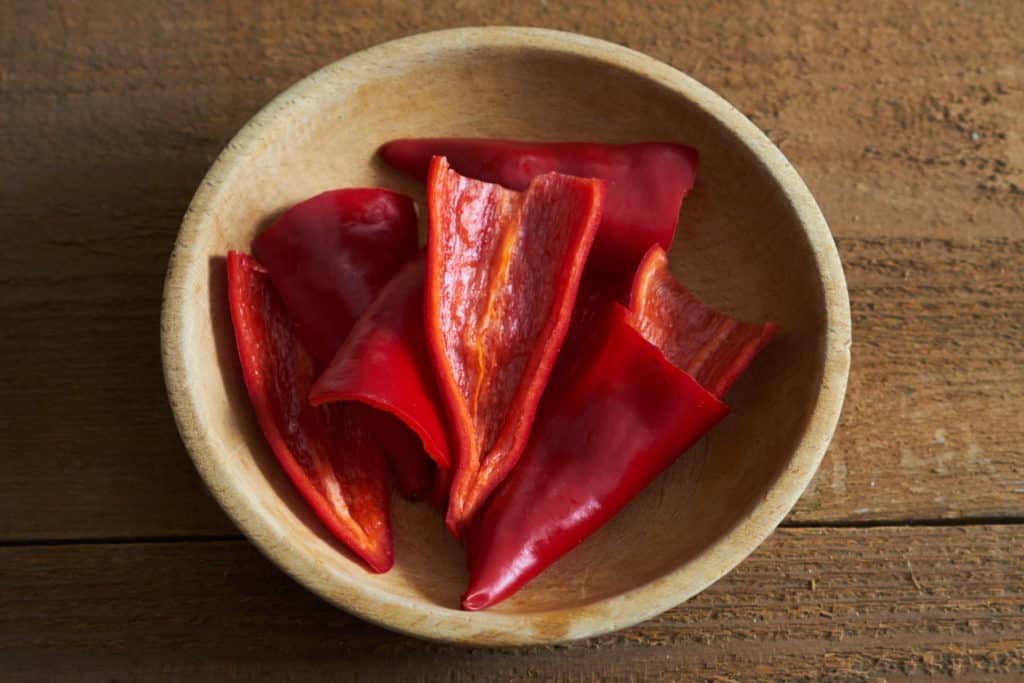 Red Fresno chiles, sliced in half and seeds removed, in a wooden bowl. 