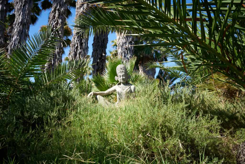 A bodhisattva statue surrouned by vegetation on the grounds of Indian Springs.