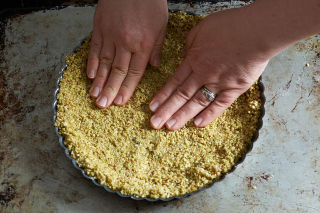 A woman's hands pressing tart crust into a pan.