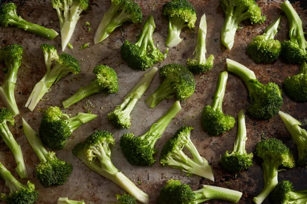 Sliced broccoli florets on a sheet pan.