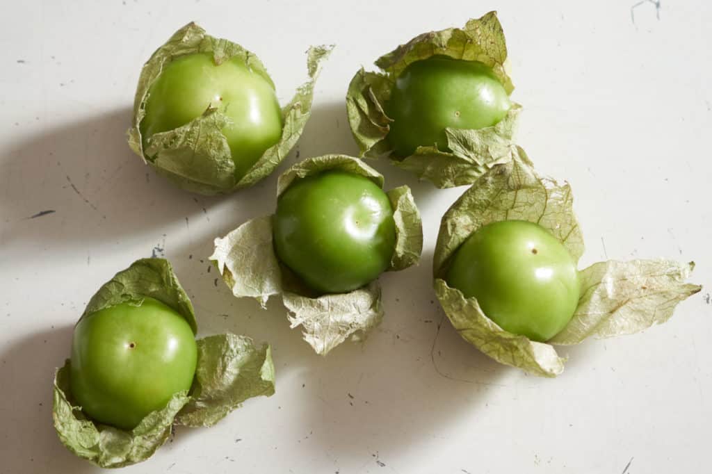Five tomatillos in their husks.