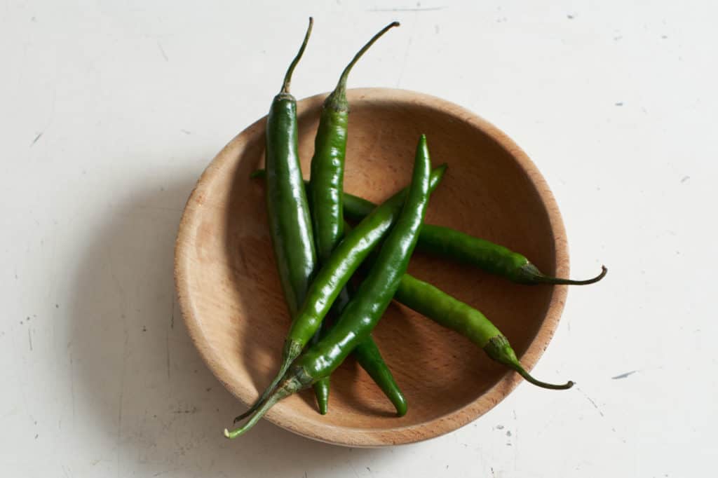 Green chiles in a wooden bowl.