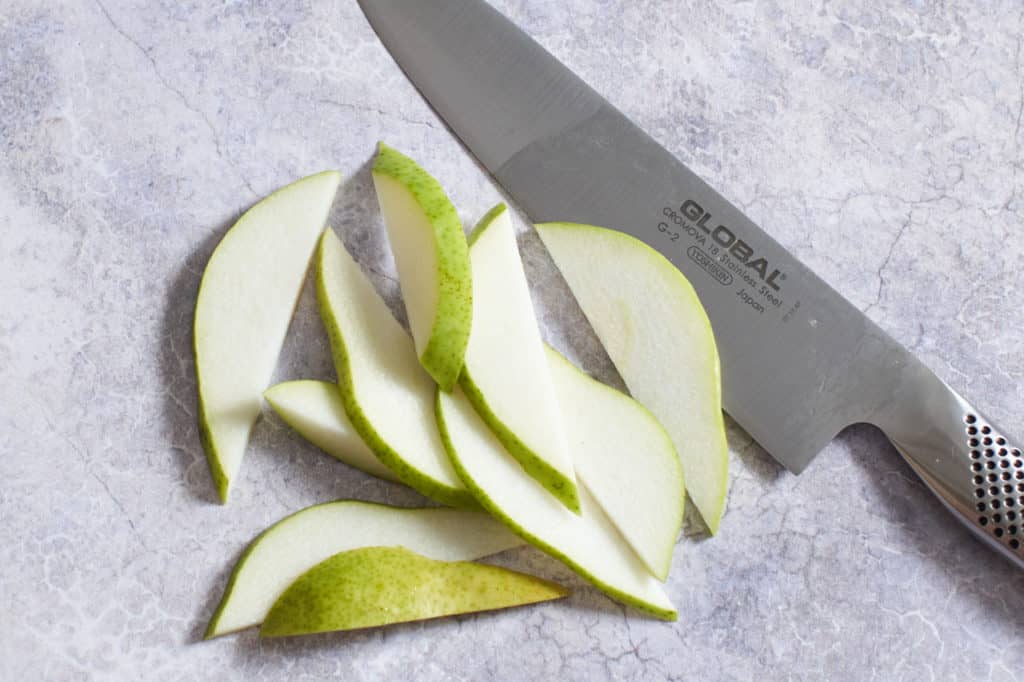 Sliced pears next to a chef's knife.