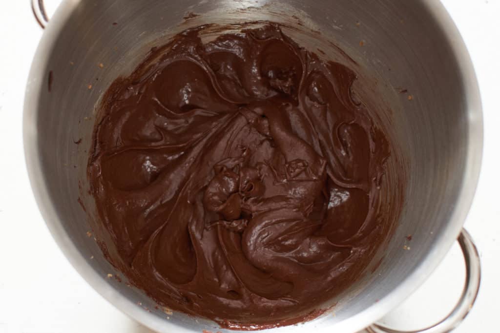 Chocolate cookie batter with wet ingredients added in a mixing bowl.