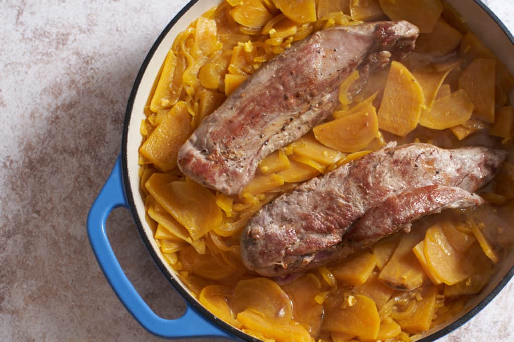 Two seared pork tenderloins added to   a casserole pan with golden beets and white wine sauce.