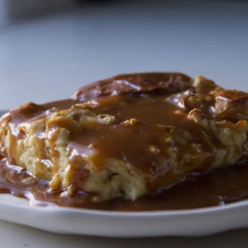 A slice of banana-pretzel bread pudding on a plate topped with caramel sauce