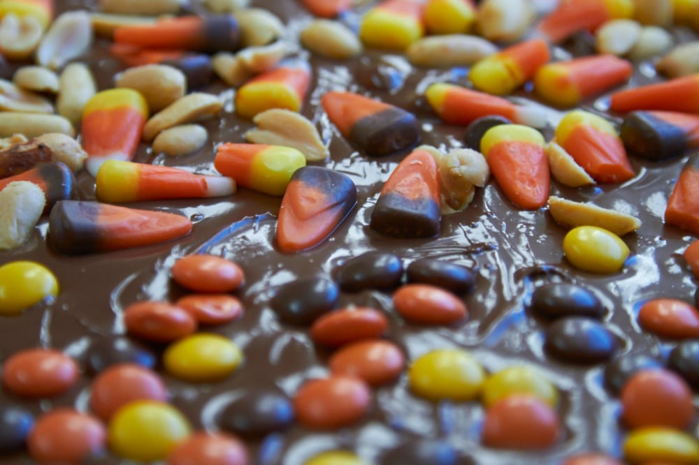 Candy corn and nuts on top of melted chocolate.