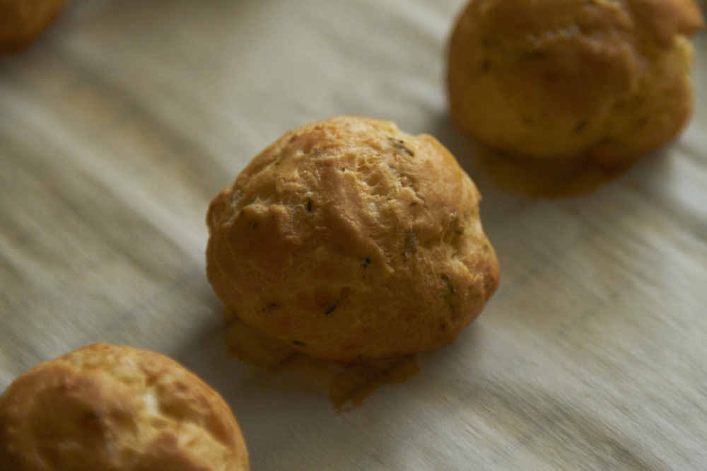 Freshly baked parmesan-rosemary gougères on a parchment lined cooling rack. 