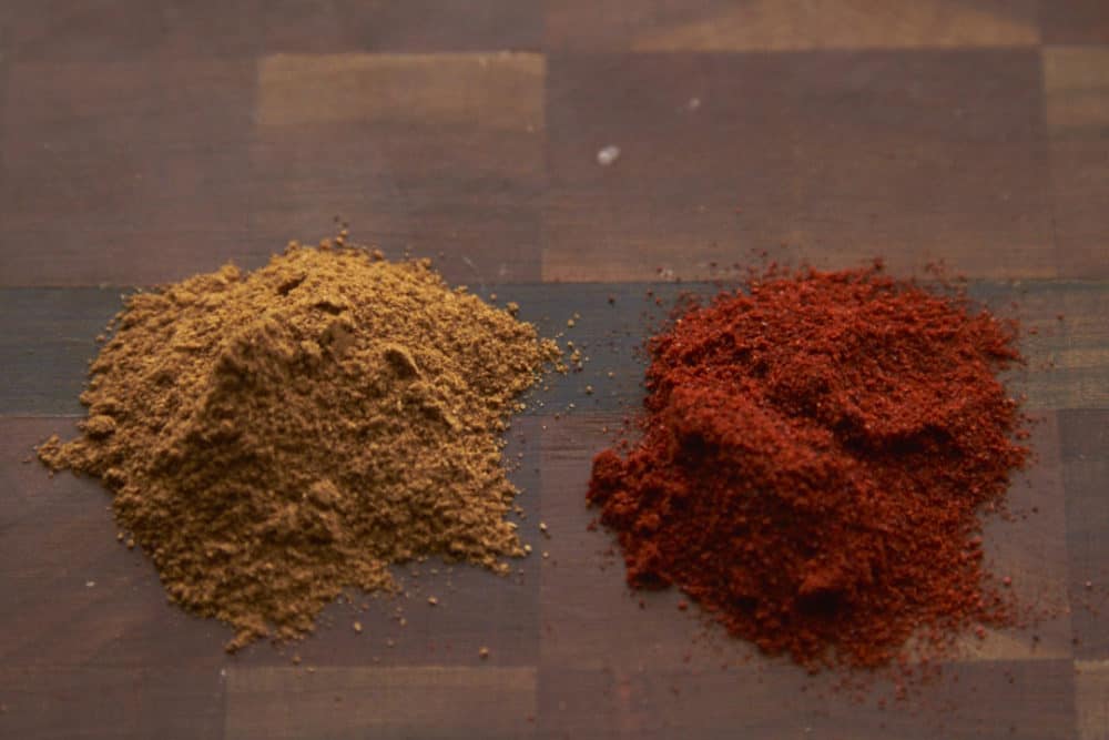 Smoked paprika and cayenne pepper on a wooden cutting board. 