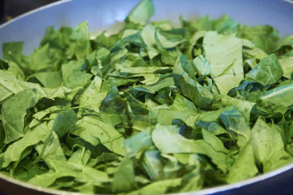 Fresh kale in a grey skillet.