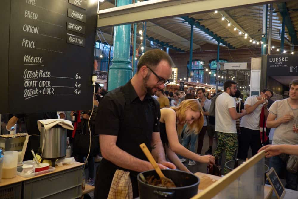 A man preparing food at a Berlin indoor market. 