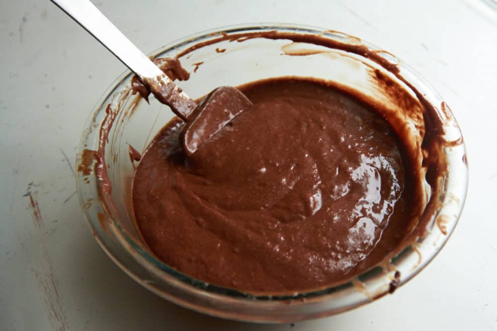 A bowl of melted chocolate with a spatula in it.
