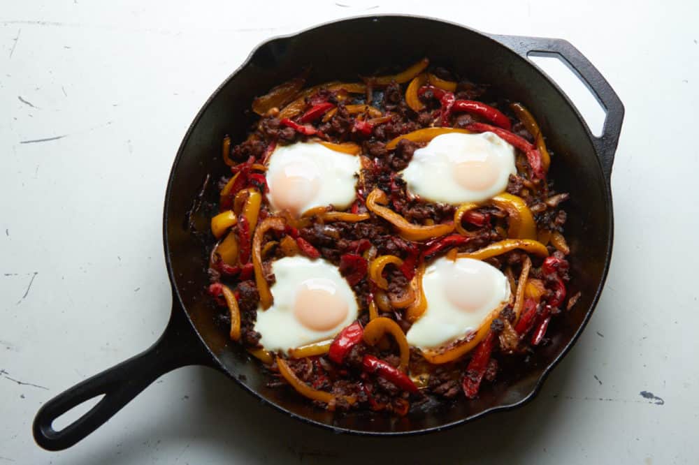 Cast iron skillet filled with piperade consisting of peppers, onions, chorizo and eggs.