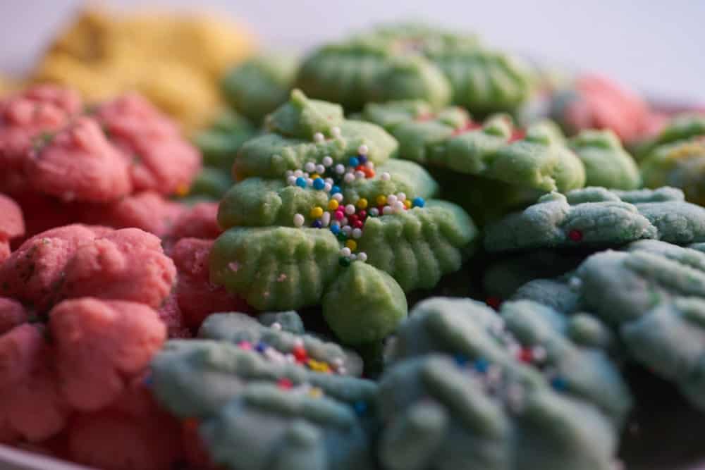 Spritz cookies in a variety of colors on a white plate. 