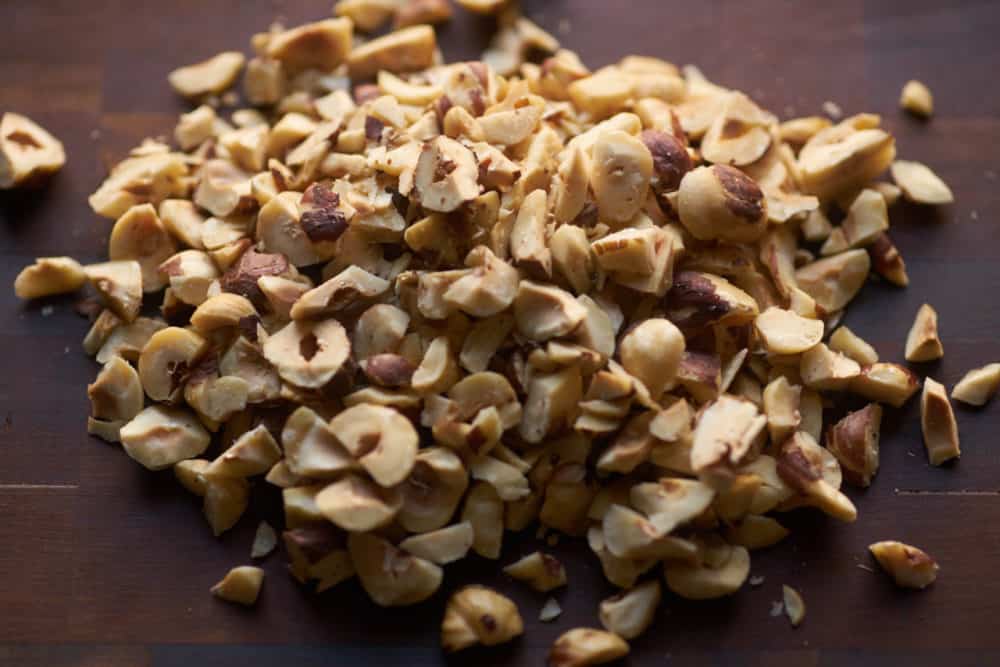 Chopped hazelnuts on a wooden cutting board.