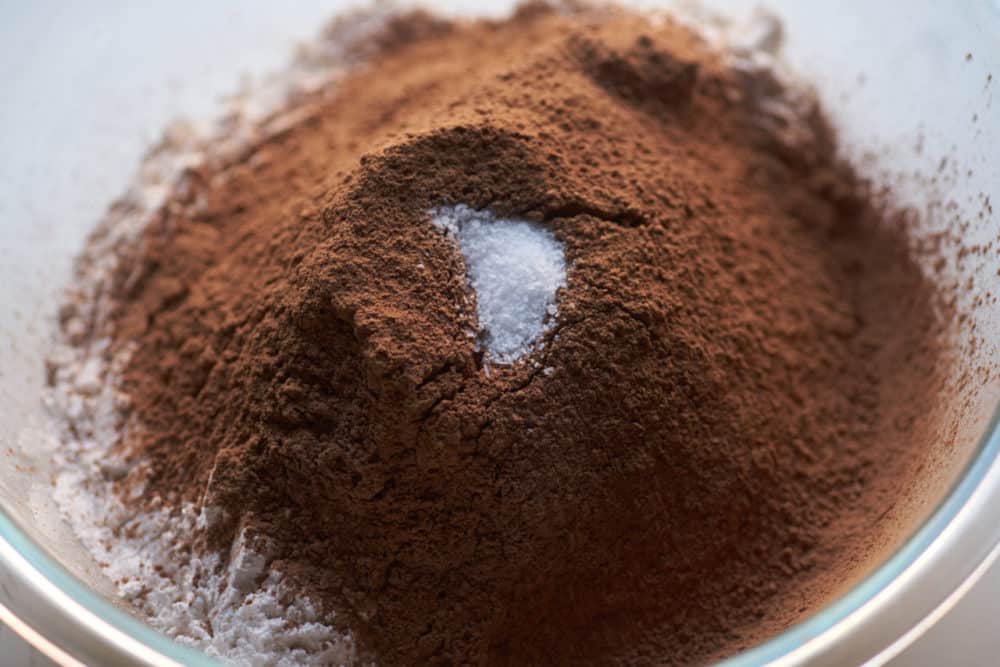 Sifted powdered sugar and cocoa powder in a glass bowl topped with kosher salt.