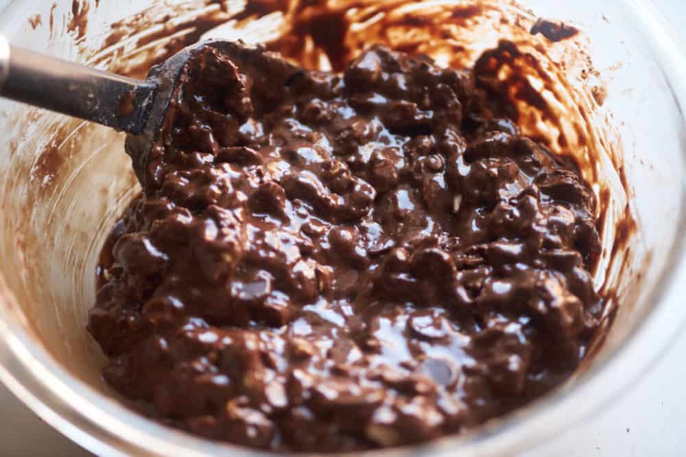 A glass bowl of cookie batter hazelnut cookies with a black spatula in it.