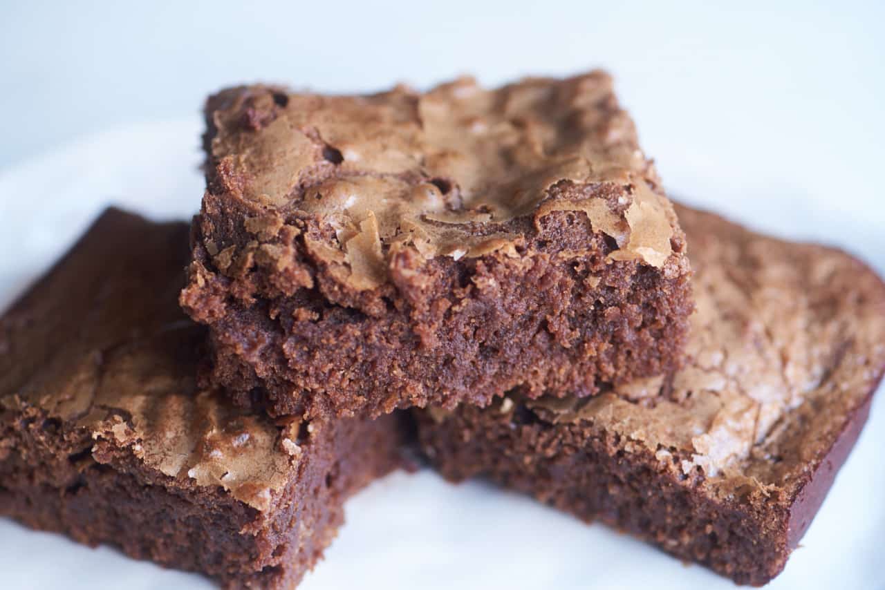 Three square-shaped brownies displayed on a white plate.