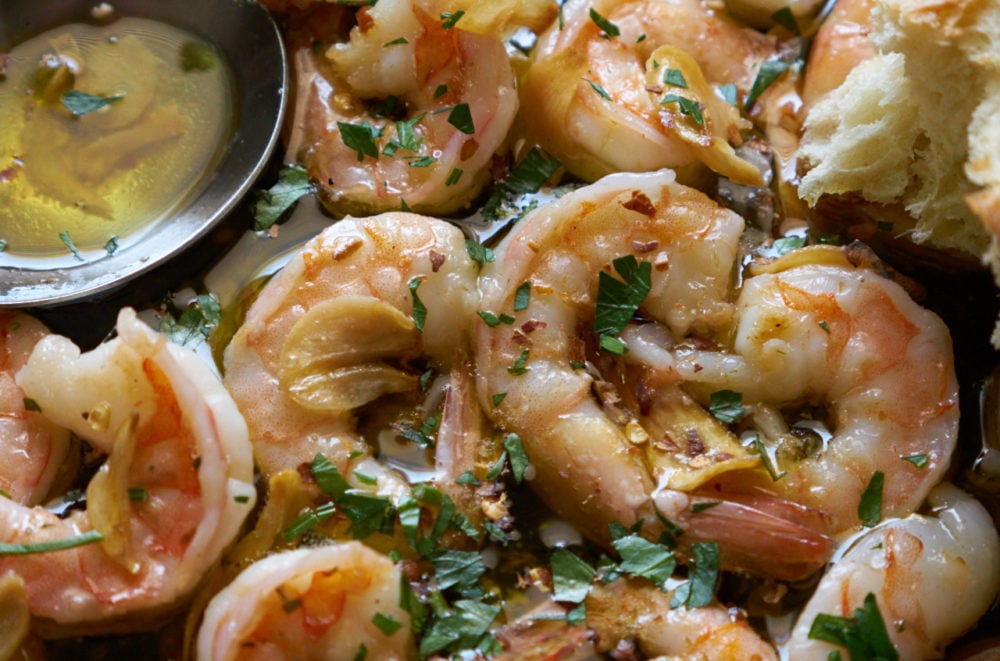 Gambas al ajillo in a skillet with a silver serving spoon.