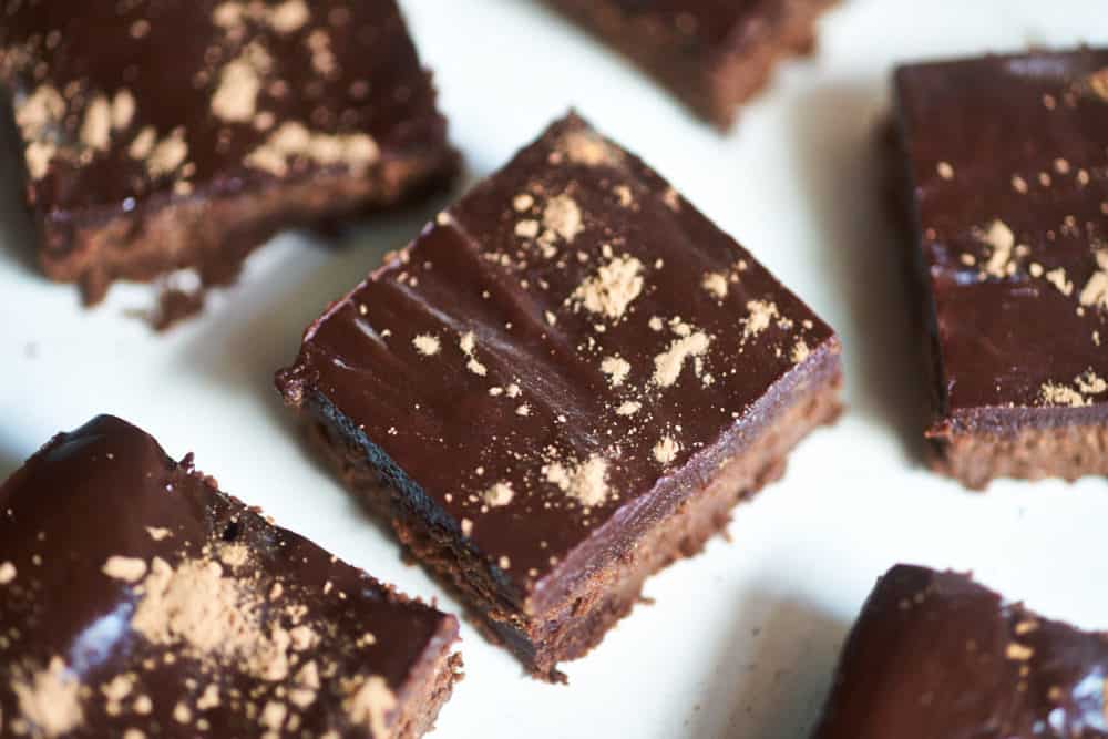 Gluten-free brownies cut into small squares and dusted with cocoa powder. 