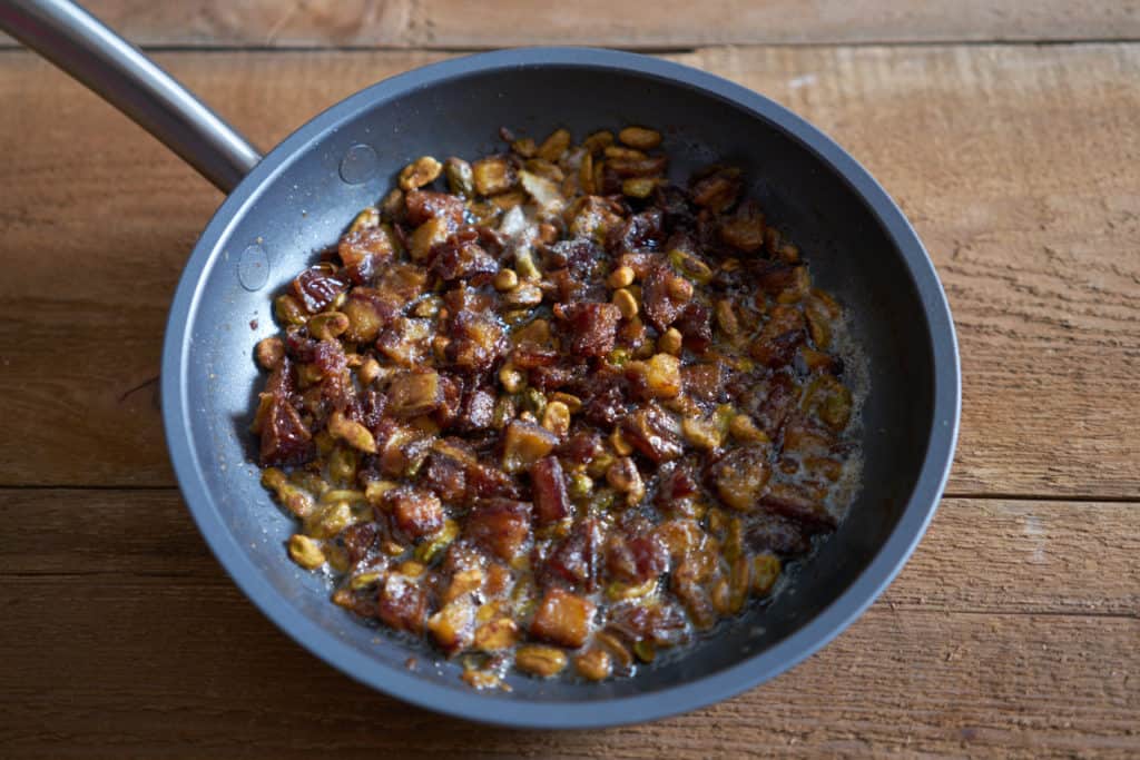 A small skillet with dates and pistachios in browned butter.