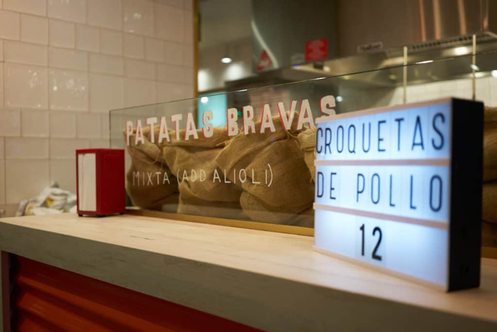Patatas bravas written on glass at a kiosk.