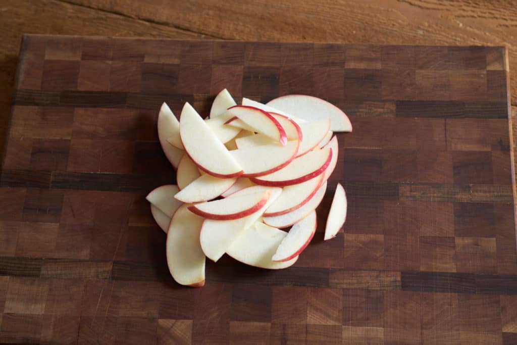 Sliced red apples on a wooden cutting board.