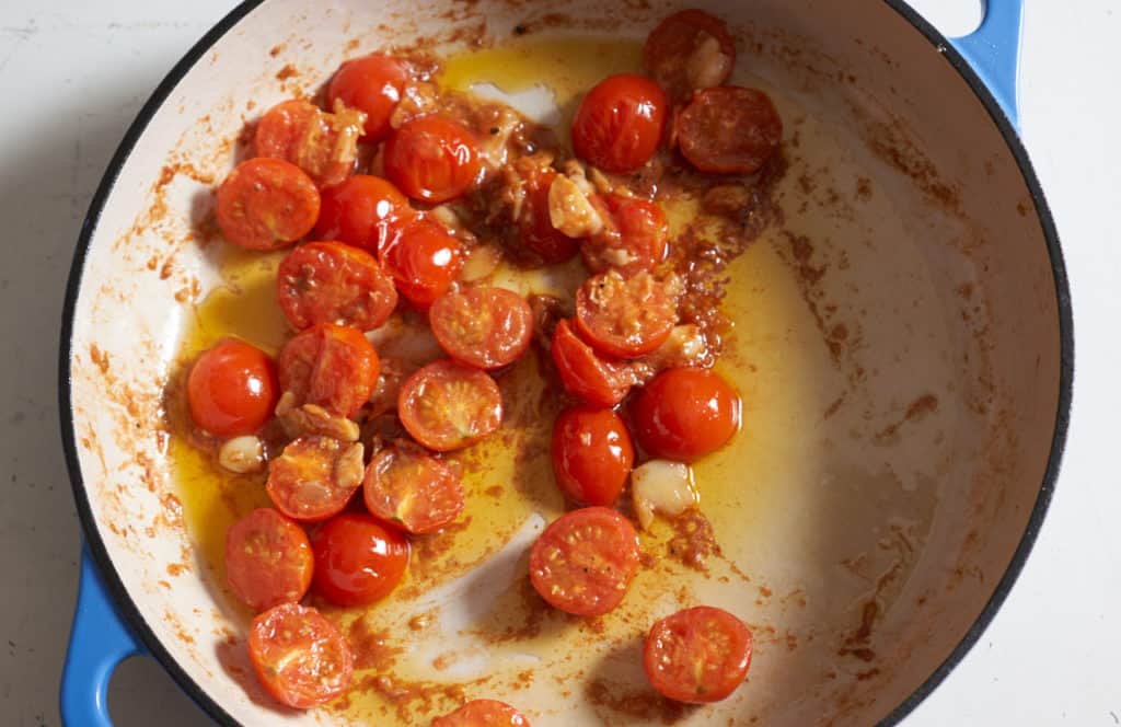 Cooked cherry tomato sauce in a blue casserole pan.