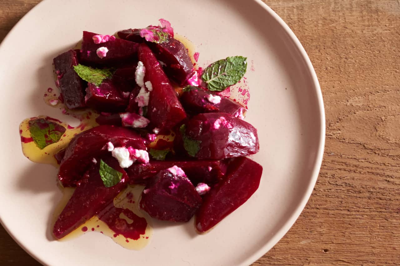 A plate of oven-roasted beets with goat cheese, orange vinaigrette, and mint.