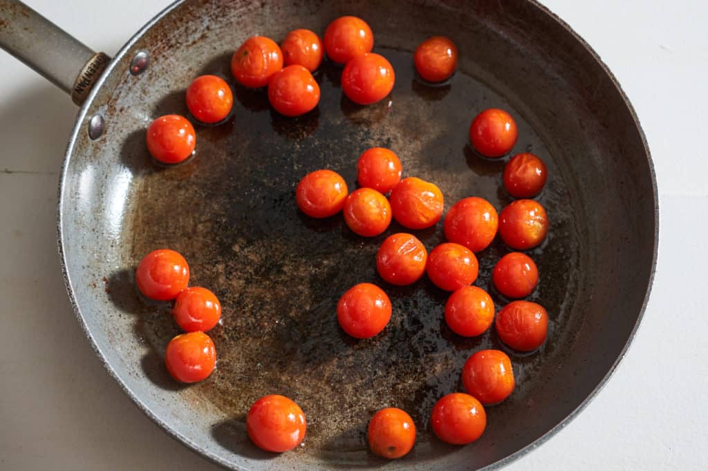 Cooked cherry tomatoes in a large skillet.
