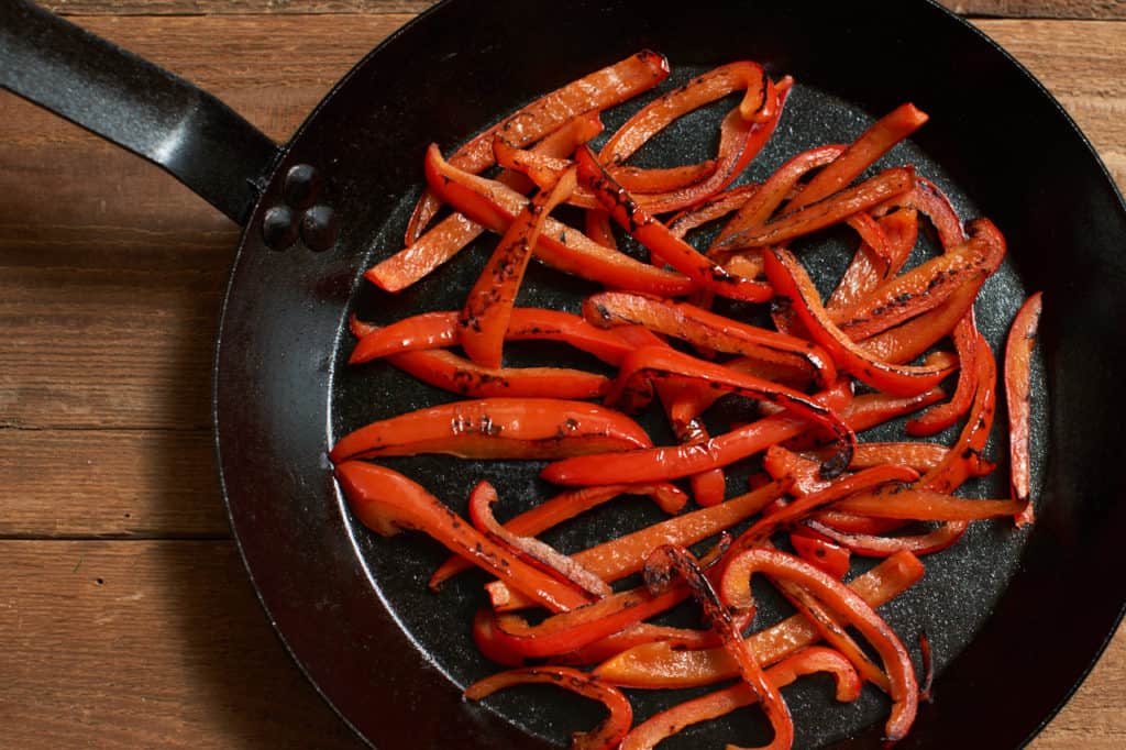 Charred red peppers in a cast iron skillet.