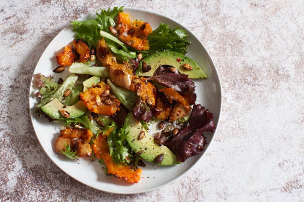 A plate of harissa roasted butternut squash salad with avocado.