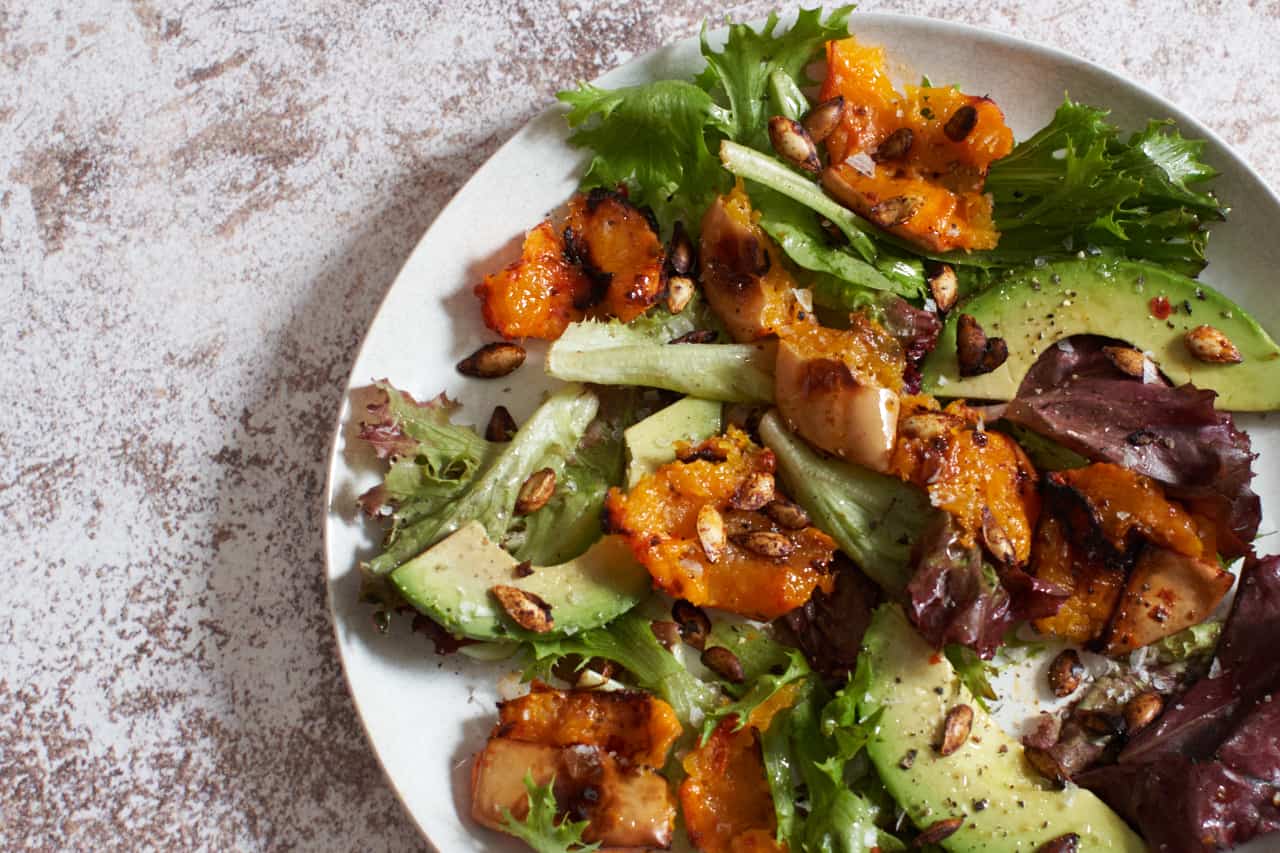 A plate of harissa roasted butternut squash salad with avocado.