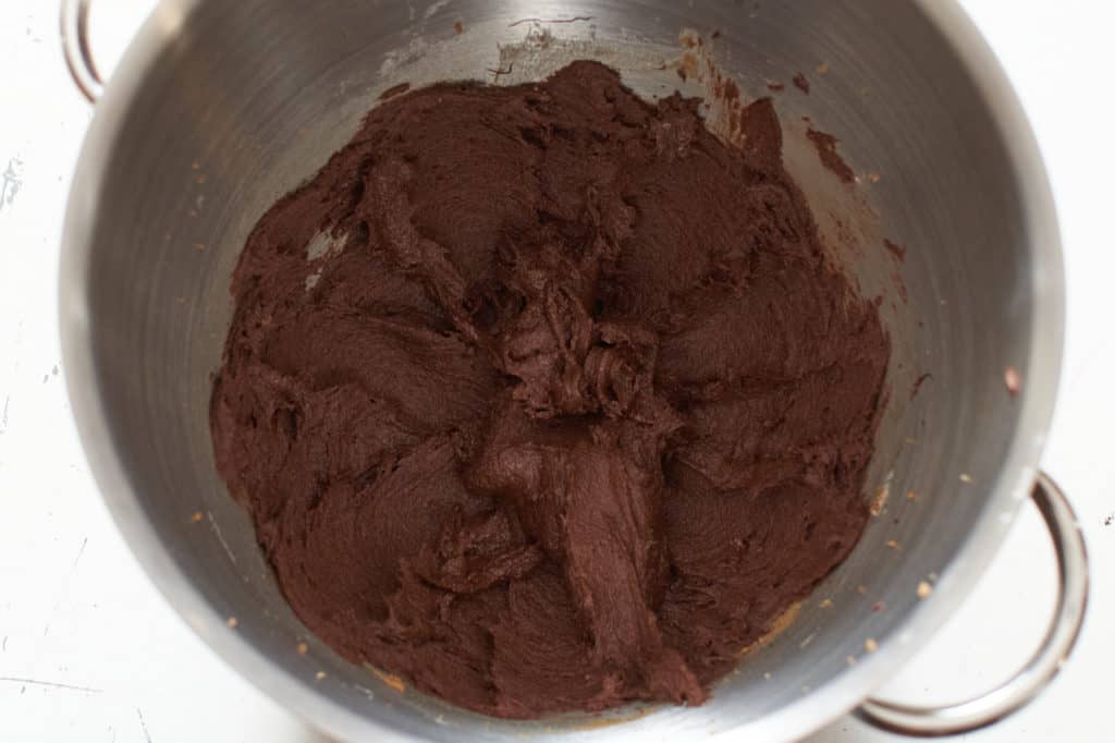 Cookie batter with dry ingredients added in a mixing bowl.