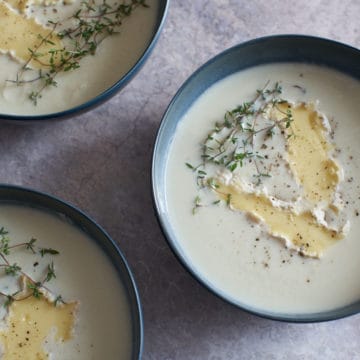 Three bowls of creamy cauliflower soup with brie