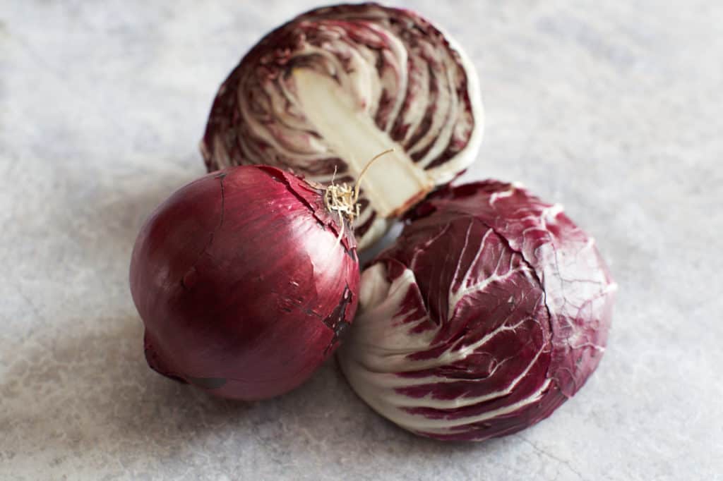 A red onion and a head of radicchio sliced in half