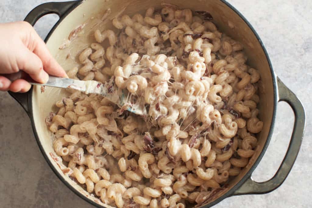 Stirring melted cheese into the cavatappi goat cheese pasta mixture