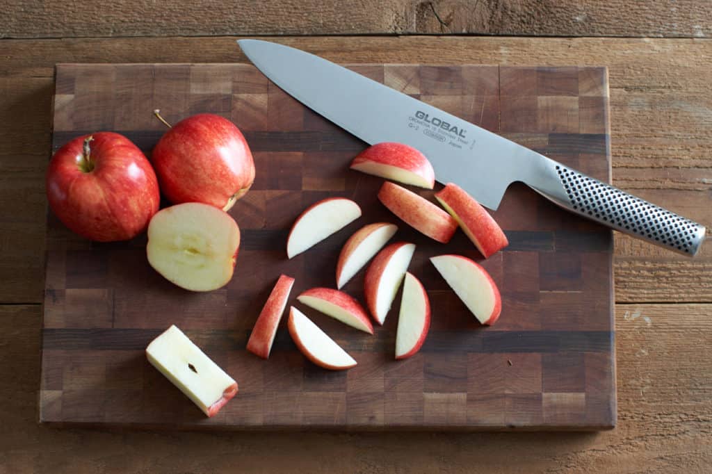 Sliced apples on a cutting board with a knife.