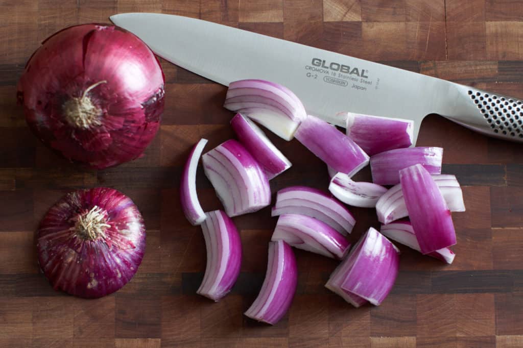 Sliced onions on a cutting board with a knife.