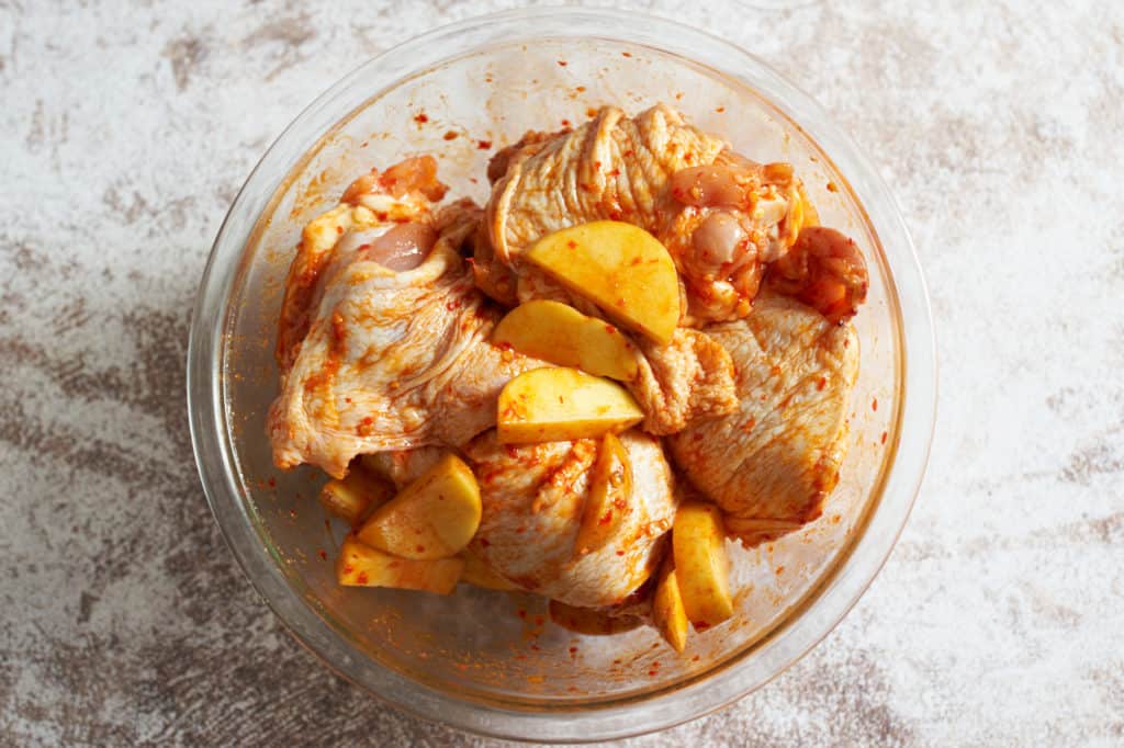 Chicken thighs and potatoes marinating in harissa and spices.