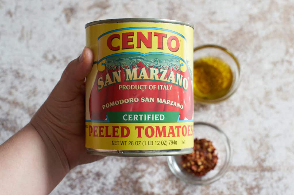 A woman's hand holing a can of san marzano tomatoes