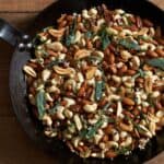 Oven roasted nuts with crispy herbs and garlic in a cast iron pan.