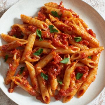 Penne all'Arrabbiata topped with parsley on a white plate.